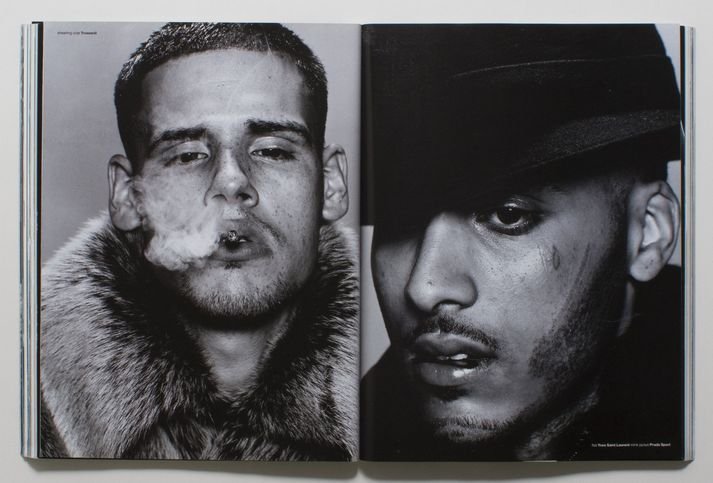 Open magazine spread with two black and white close-up portraits of men, one in a fur collar, one in a hat