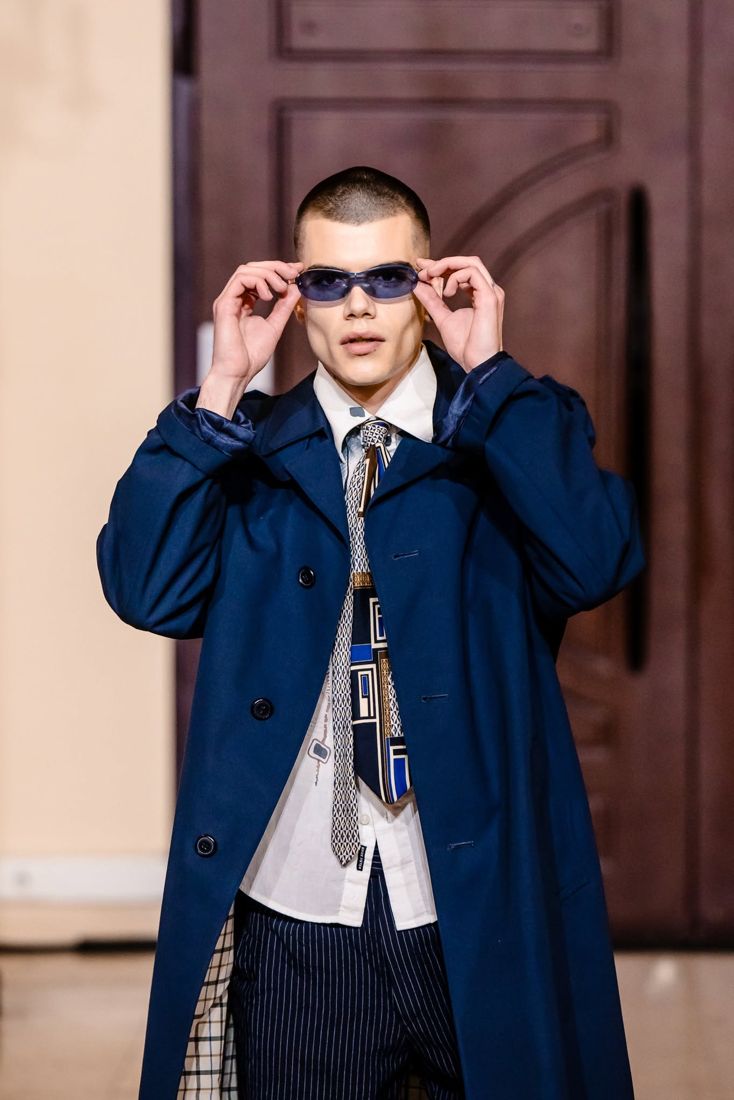 Look 12: Navy overcoat, layered ties, pinstripe trousers, blue lenses