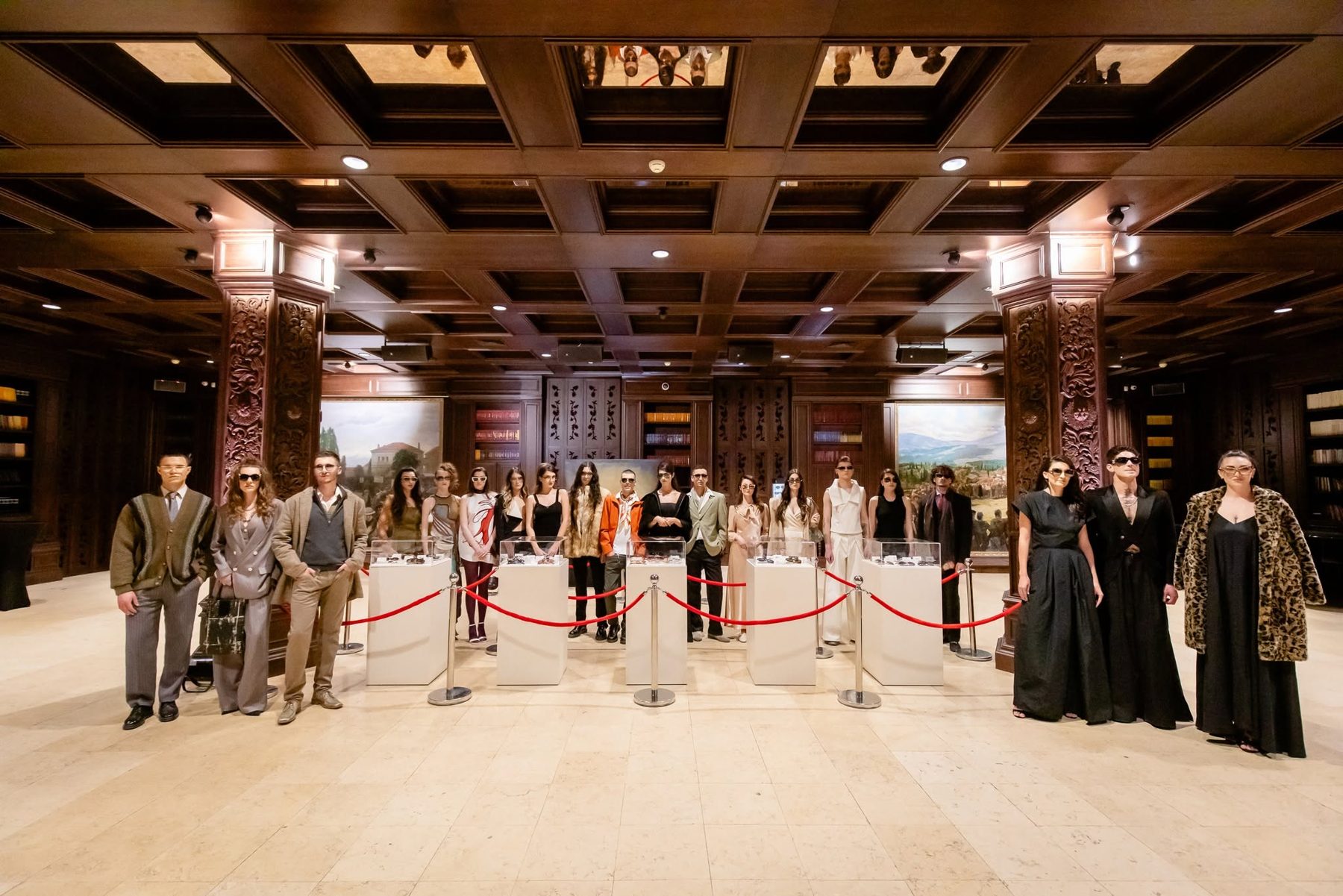 All the models from the show lined up together in a wood-panelled hall, wearing sunglasses beside eyewear display cases
